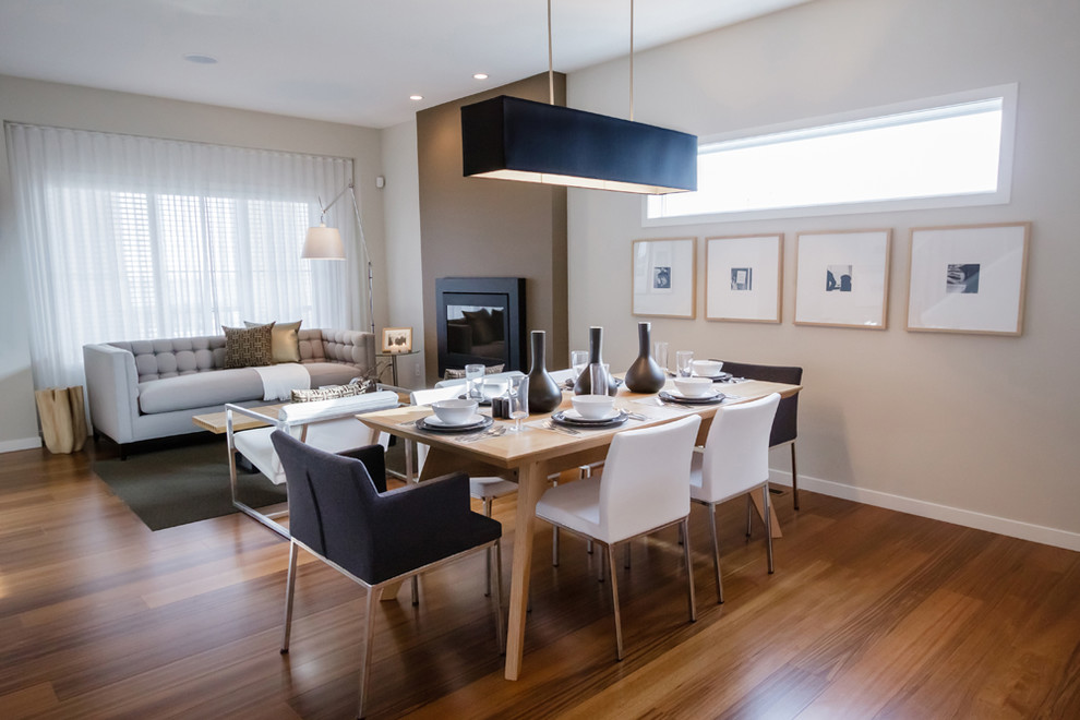 Photo of a modern dining room in Calgary with beige walls and dark hardwood floors.