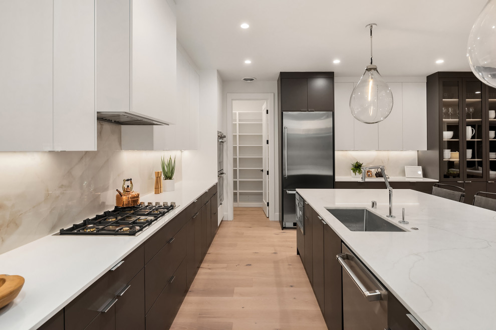 Inspiration for an expansive modern galley open plan kitchen in Seattle with a submerged sink, flat-panel cabinets, white cabinets, engineered stone countertops, multi-coloured splashback, porcelain splashback, stainless steel appliances, light hardwood flooring, an island and white worktops.