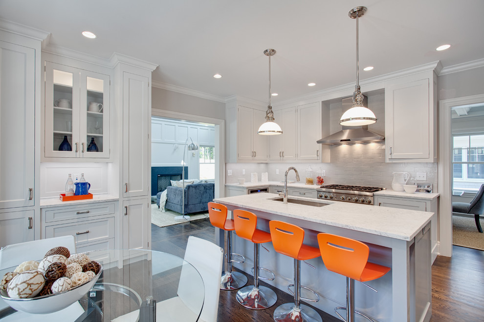 Eat-in kitchen - large transitional u-shaped medium tone wood floor and brown floor eat-in kitchen idea with an undermount sink, flat-panel cabinets, white cabinets, marble countertops, white backsplash, subway tile backsplash, stainless steel appliances and an island
