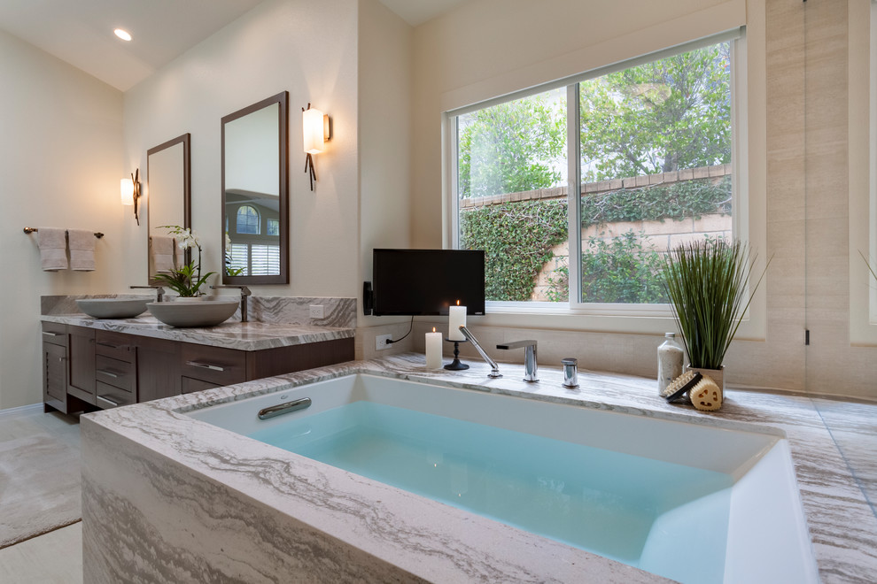 Design ideas for a mid-sized transitional master bathroom in Los Angeles with louvered cabinets, dark wood cabinets, an undermount tub, a corner shower, pebble tile, beige walls, porcelain floors, a vessel sink, engineered quartz benchtops, beige floor, a hinged shower door and multi-coloured benchtops.