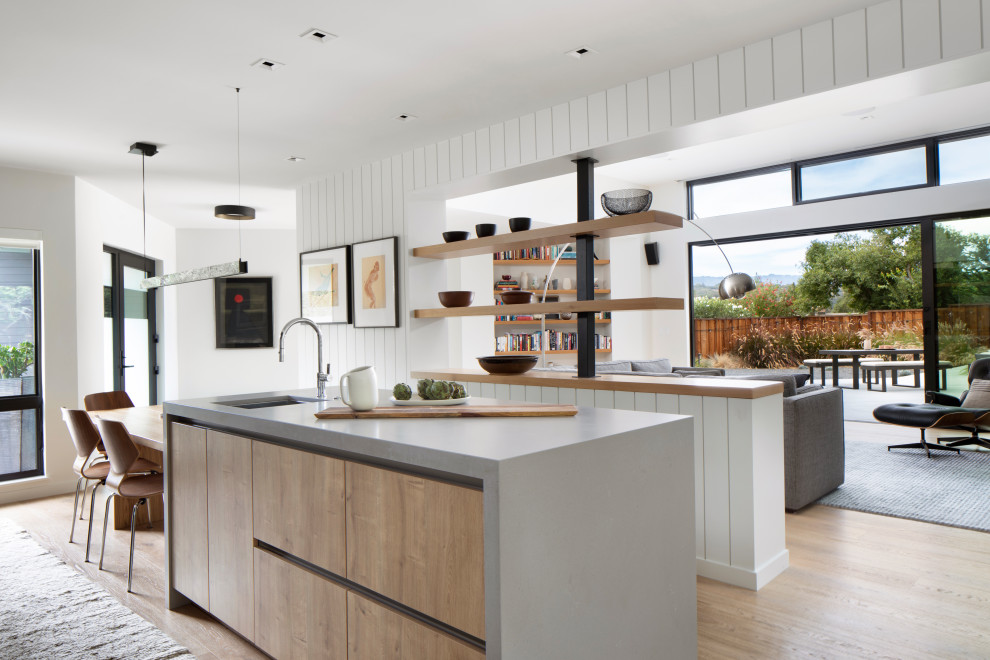 Mid-sized scandinavian galley eat-in kitchen in San Francisco with a single-bowl sink, flat-panel cabinets, brown cabinets, quartzite benchtops, grey splashback, engineered quartz splashback, panelled appliances, light hardwood floors, with island, brown floor and grey benchtop.
