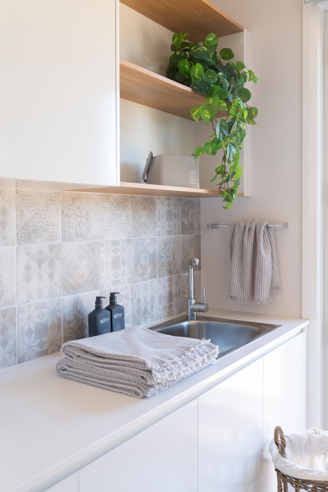 Contemporary galley laundry room in Canberra - Queanbeyan with a single-bowl sink, porcelain splashback, porcelain floors, a stacked washer and dryer and grey floor.