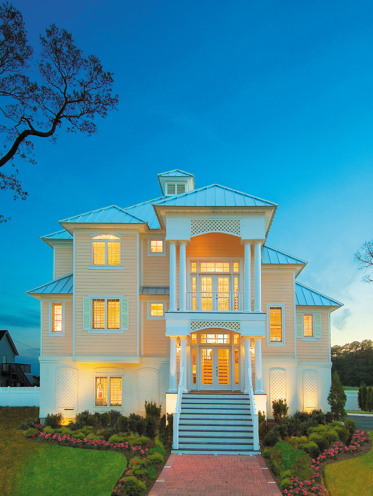 Inspiration for a large beach style three-storey beige exterior in Miami with vinyl siding and a hip roof.