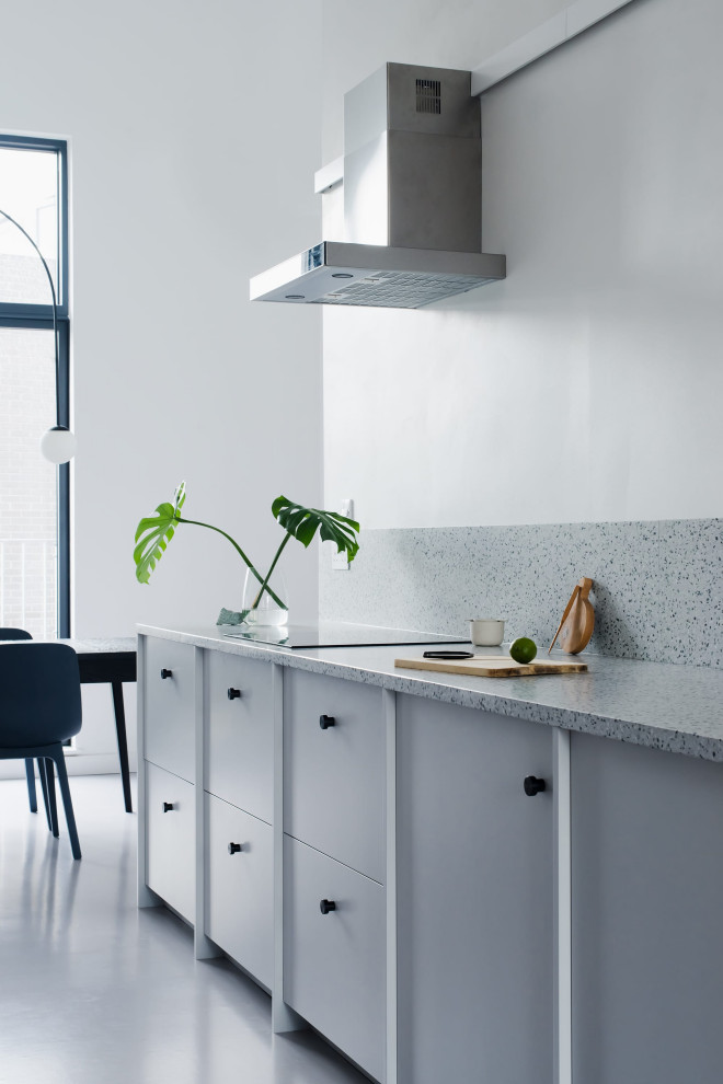 Large contemporary galley eat-in kitchen in London with a drop-in sink, flat-panel cabinets, grey cabinets, terrazzo benchtops, black appliances, no island and vaulted.