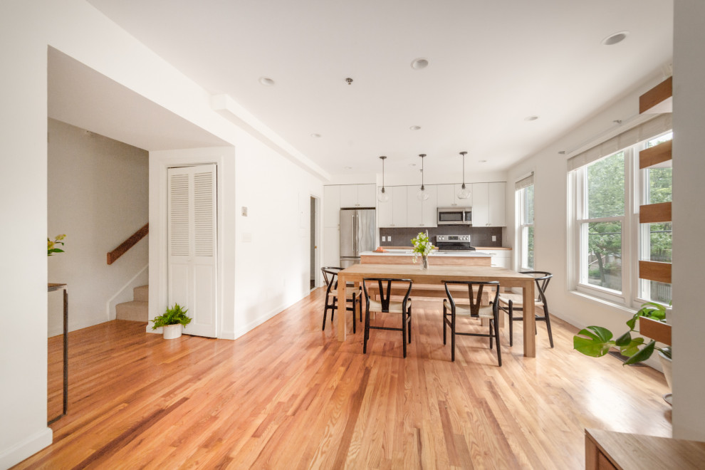 Example of a mid-sized trendy single-wall medium tone wood floor and brown floor eat-in kitchen design in Boston with an undermount sink, flat-panel cabinets, white cabinets, wood countertops, gray backsplash, porcelain backsplash, stainless steel appliances, an island and brown countertops