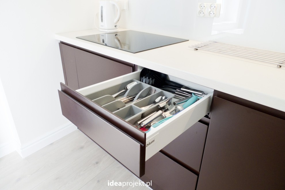 Eat-in kitchen - mid-sized eclectic galley light wood floor eat-in kitchen idea with a single-bowl sink, flat-panel cabinets, brown cabinets, laminate countertops, white backsplash, glass sheet backsplash, stainless steel appliances and no island