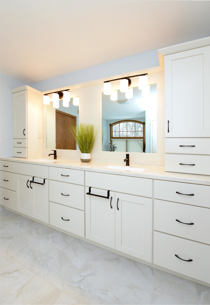 Example of a mid-sized transitional master white tile and stone tile porcelain tile and white floor corner bathtub design with shaker cabinets, white cabinets, a one-piece toilet, blue walls, an integrated sink, solid surface countertops, a hinged shower door and white countertops