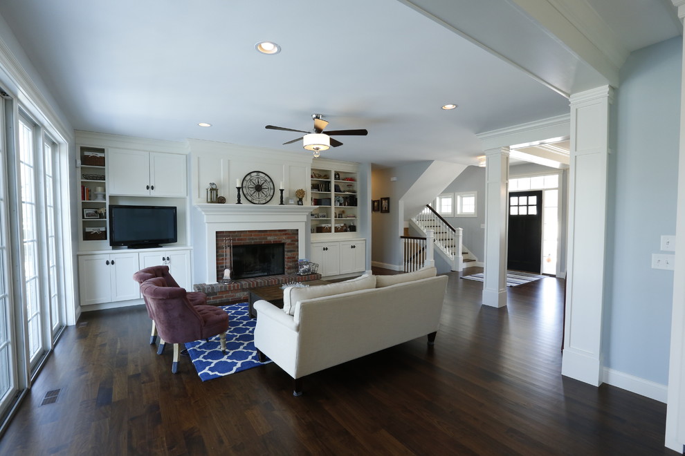 Inspiration for a mid-sized arts and crafts open concept living room in Cedar Rapids with blue walls, dark hardwood floors, a standard fireplace, a brick fireplace surround and a built-in media wall.