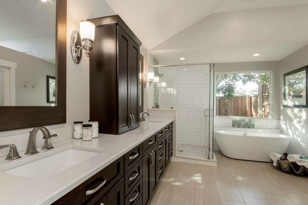 Photo of a mid-sized contemporary master bathroom in Los Angeles with shaker cabinets, dark wood cabinets, a curbless shower, a one-piece toilet, multi-coloured tile, porcelain tile, beige walls, plywood floors, an integrated sink, solid surface benchtops, beige floor, a sliding shower screen and white benchtops.