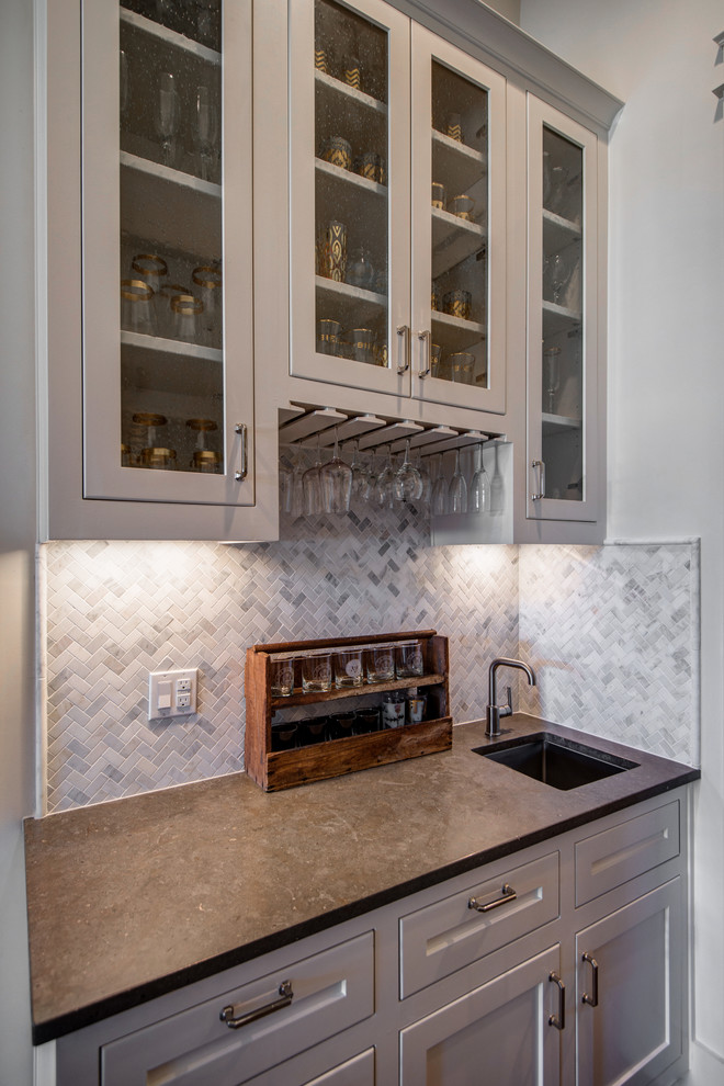 This is an example of a transitional home bar in Austin with marble splashback.