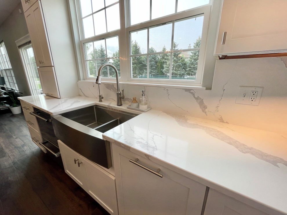Large transitional u-shaped medium tone wood floor and brown floor eat-in kitchen photo in Chicago with a farmhouse sink, shaker cabinets, white cabinets, quartz countertops, white backsplash, quartz backsplash, stainless steel appliances, two islands and white countertops
