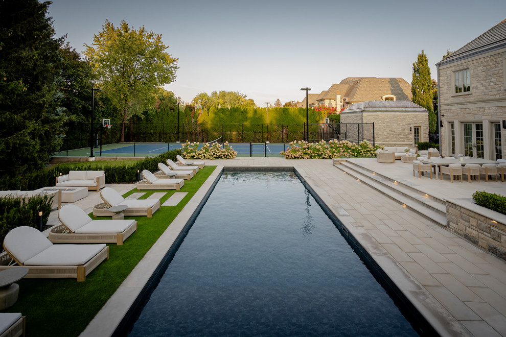 Exemple d'un grand piscine avec aménagement paysager arrière tendance rectangle avec des pavés en béton.