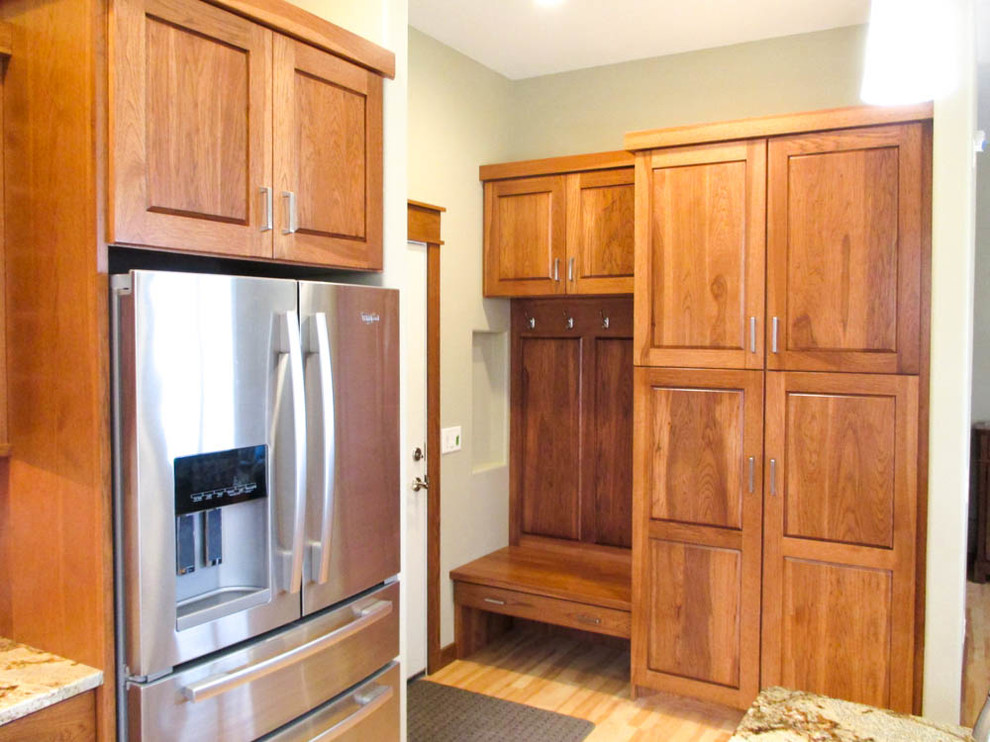 This is an example of a mid-sized traditional l-shaped eat-in kitchen in Other with an undermount sink, raised-panel cabinets, medium wood cabinets, granite benchtops, stainless steel appliances, with island, light hardwood floors and brown floor.
