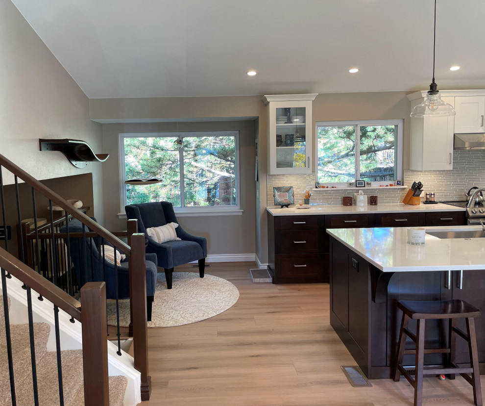 Large traditional l-shaped open plan kitchen in Denver with a single-bowl sink, shaker cabinets, engineered stone countertops, grey splashback, glass sheet splashback, stainless steel appliances, vinyl flooring, an island, beige floors and a vaulted ceiling.