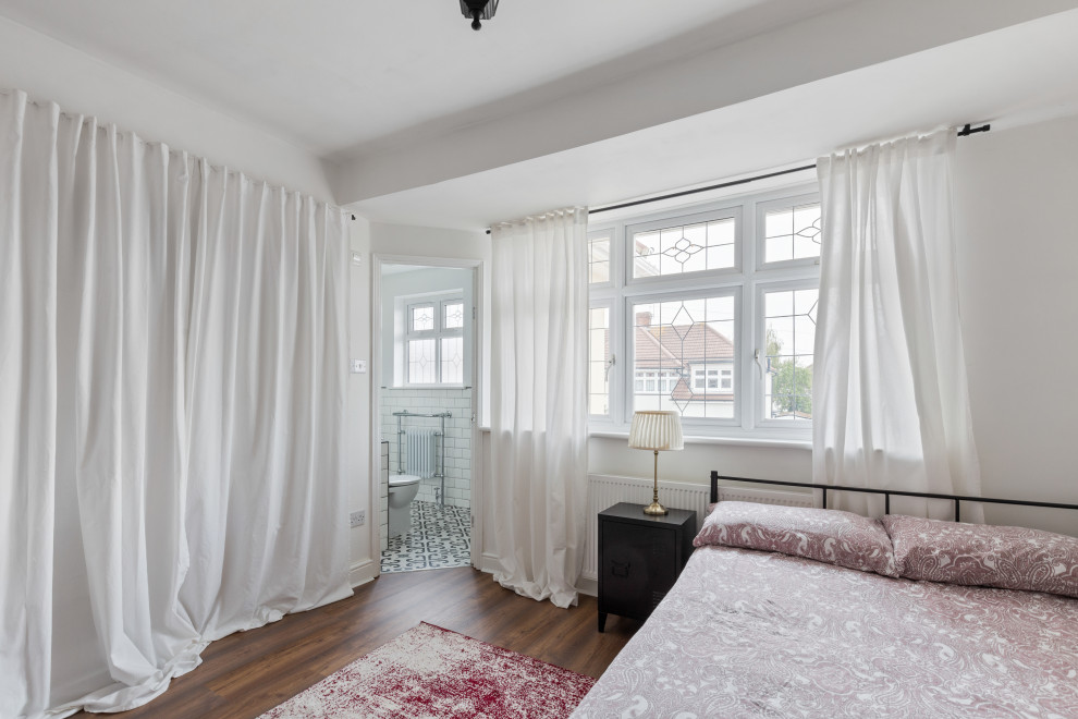 Photo of a mid-sized contemporary master bedroom in Essex with white walls, laminate floors and brown floor.