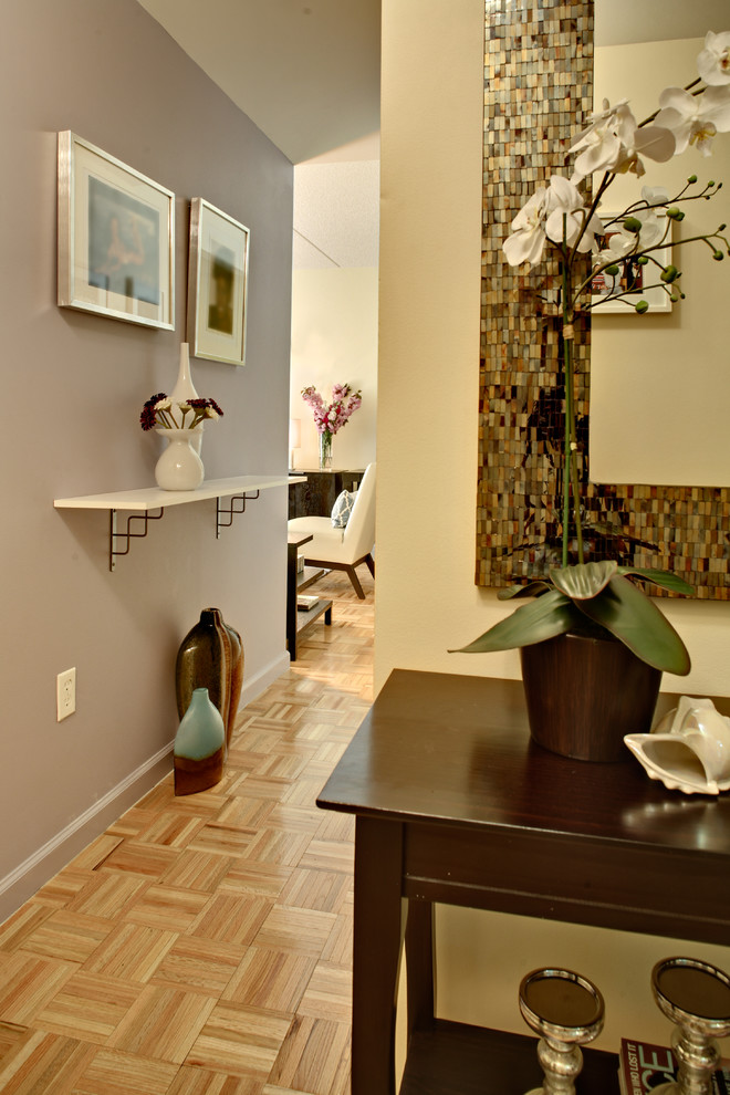 This is an example of a mid-sized traditional hallway in New York with light hardwood floors, grey walls and brown floor.