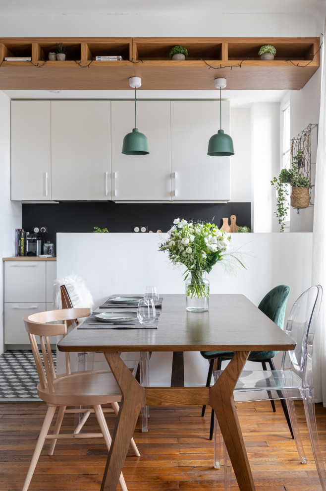 Exemple d'une salle à manger ouverte sur la cuisine tendance de taille moyenne avec un mur blanc et un sol en bois brun.