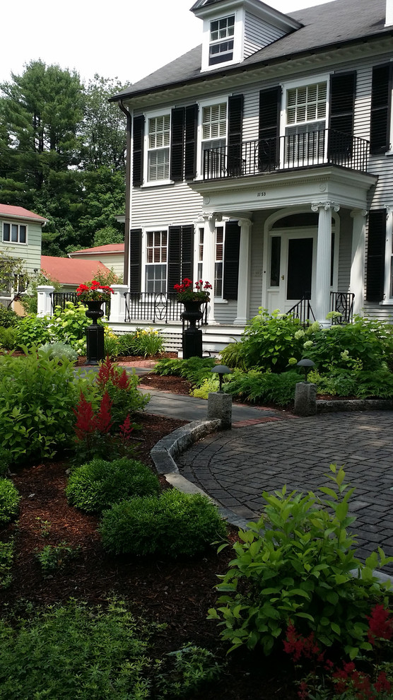 Large traditional front yard shaded driveway in Boston with brick pavers for summer.