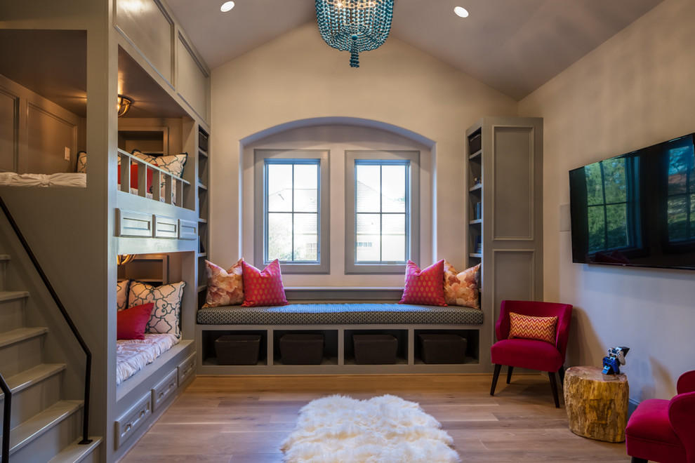 This is an example of a large transitional kids' bedroom for girls in Houston with beige walls and light hardwood floors.