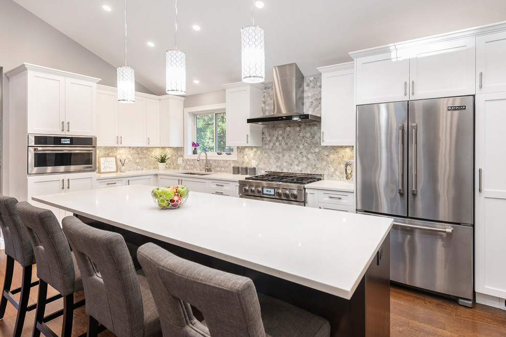 Example of a large transitional l-shaped medium tone wood floor and brown floor eat-in kitchen design in Vancouver with an undermount sink, shaker cabinets, white cabinets, quartzite countertops, multicolored backsplash, marble backsplash, stainless steel appliances, an island and white countertops