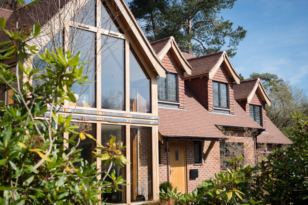 Photo of a large country two-storey brick exterior in Sussex with a gable roof and a tile roof.