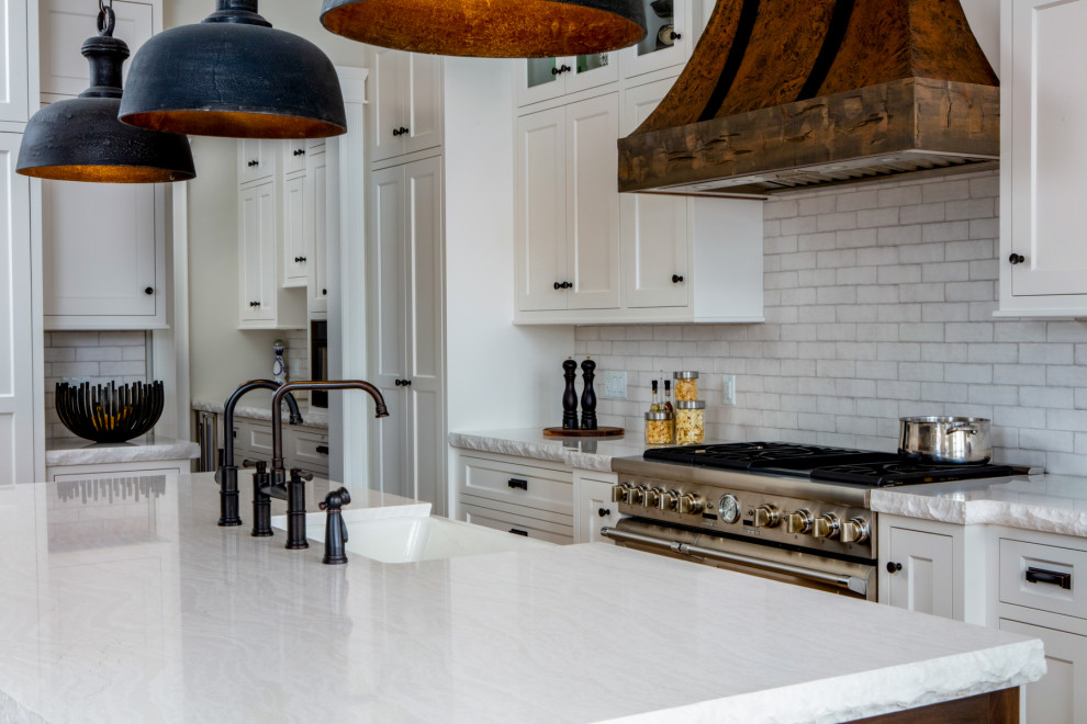 Example of a large mountain style l-shaped light wood floor and beige floor eat-in kitchen design in Toronto with a farmhouse sink, shaker cabinets, white cabinets, quartz countertops, white backsplash, subway tile backsplash, paneled appliances, an island and white countertops