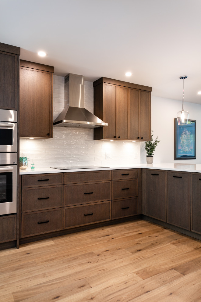 Open concept kitchen - mid-sized transitional u-shaped medium tone wood floor and brown floor open concept kitchen idea in Vancouver with an undermount sink, shaker cabinets, dark wood cabinets, quartz countertops, white backsplash, porcelain backsplash, stainless steel appliances, a peninsula and white countertops