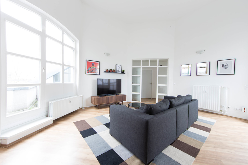 Design ideas for a mid-sized scandinavian enclosed family room in Berlin with white walls, light hardwood floors, no fireplace, a freestanding tv and beige floor.