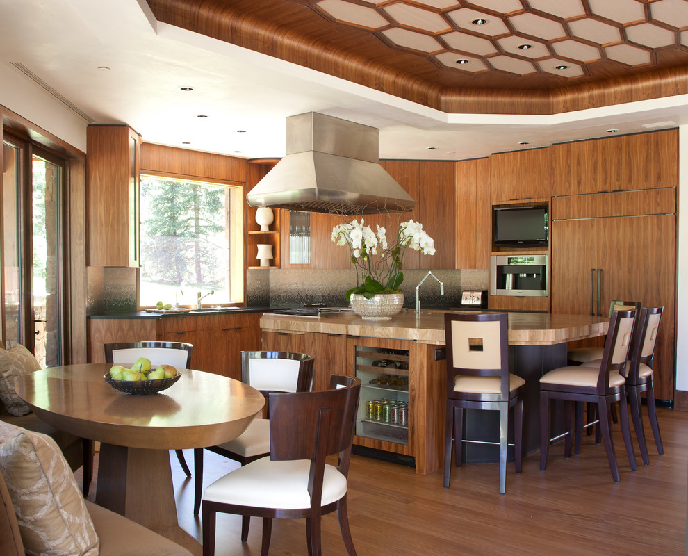 Inspiration for a transitional l-shaped eat-in kitchen in Denver with flat-panel cabinets, medium wood cabinets, wood benchtops, panelled appliances, medium hardwood floors, with island, brown floor and beige benchtop.