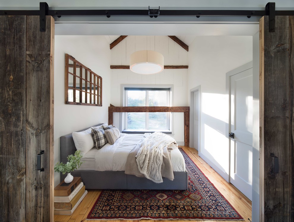 Photo of a country guest bedroom in Boston with medium hardwood floors, no fireplace, white walls and brown floor.