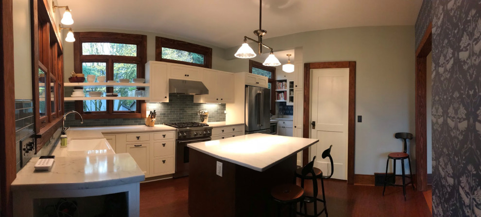 This is an example of an arts and crafts kitchen pantry in Seattle with an undermount sink, shaker cabinets, white cabinets, onyx benchtops, green splashback, glass tile splashback, stainless steel appliances, medium hardwood floors, with island and white benchtop.