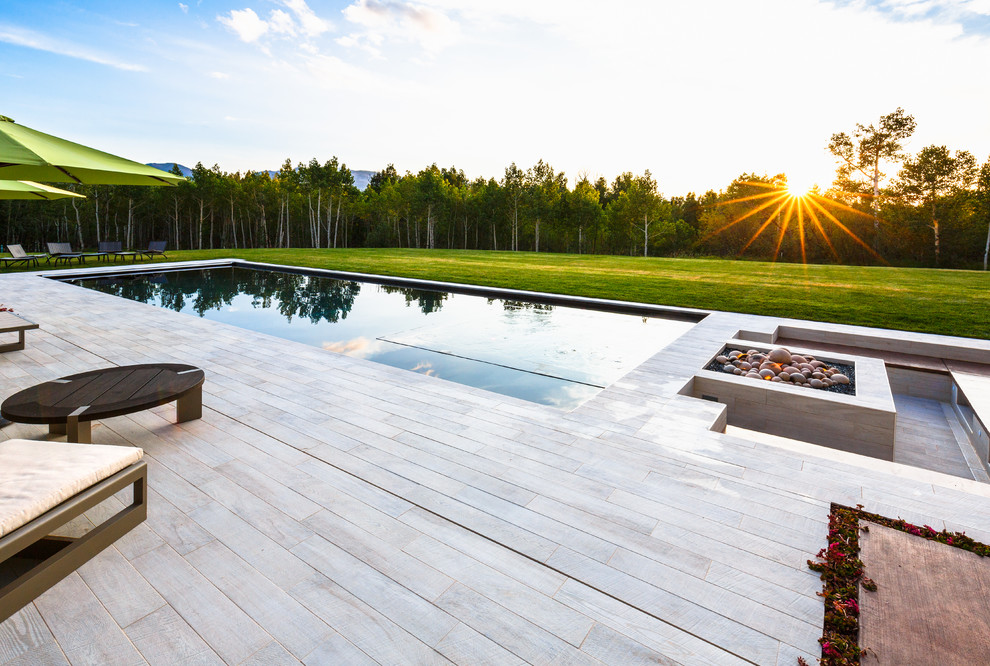This is an example of a mid-sized contemporary backyard rectangular pool in Denver with decking.