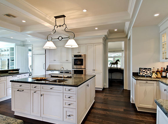 Inspiration for a large transitional l-shaped dark wood floor and brown floor eat-in kitchen remodel in Tampa with raised-panel cabinets, white cabinets, marble countertops, white backsplash, stainless steel appliances, an island, an undermount sink and metal backsplash