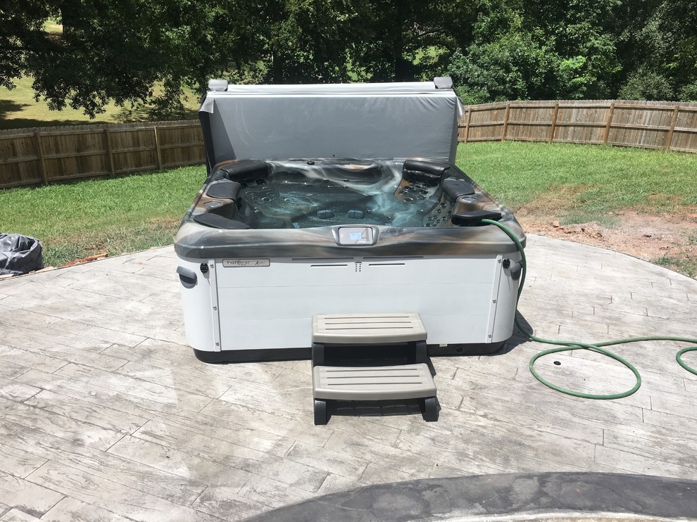 Example of a mid-sized transitional backyard stamped concrete and rectangular hot tub design