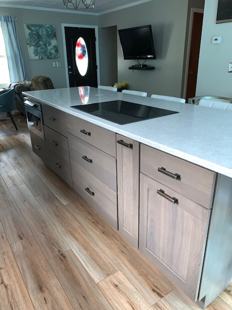 Example of a mid-sized transitional l-shaped medium tone wood floor and brown floor eat-in kitchen design in Boston with an undermount sink, shaker cabinets, brown cabinets, quartz countertops, white backsplash, stainless steel appliances, an island and beige countertops