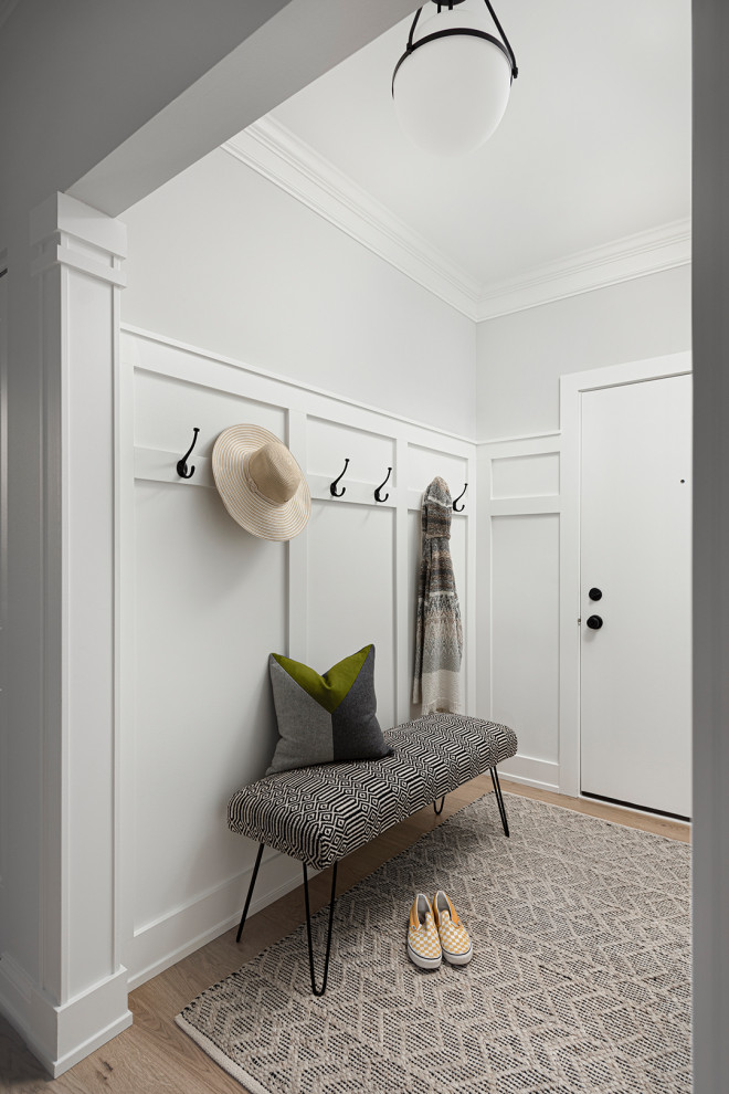 На фото: фойе среднего размера в стиле неоклассика (современная классика) с серыми стенами, светлым паркетным полом, одностворчатой входной дверью, белой входной дверью, белым полом и панелями на части стены с