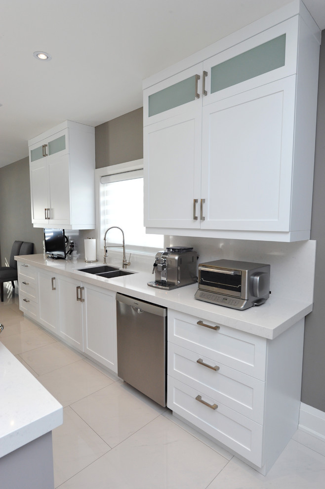 Mid-sized transitional l-shaped porcelain tile kitchen pantry photo in Toronto with a double-bowl sink, shaker cabinets, white cabinets, quartz countertops, white backsplash, stone slab backsplash, stainless steel appliances and an island