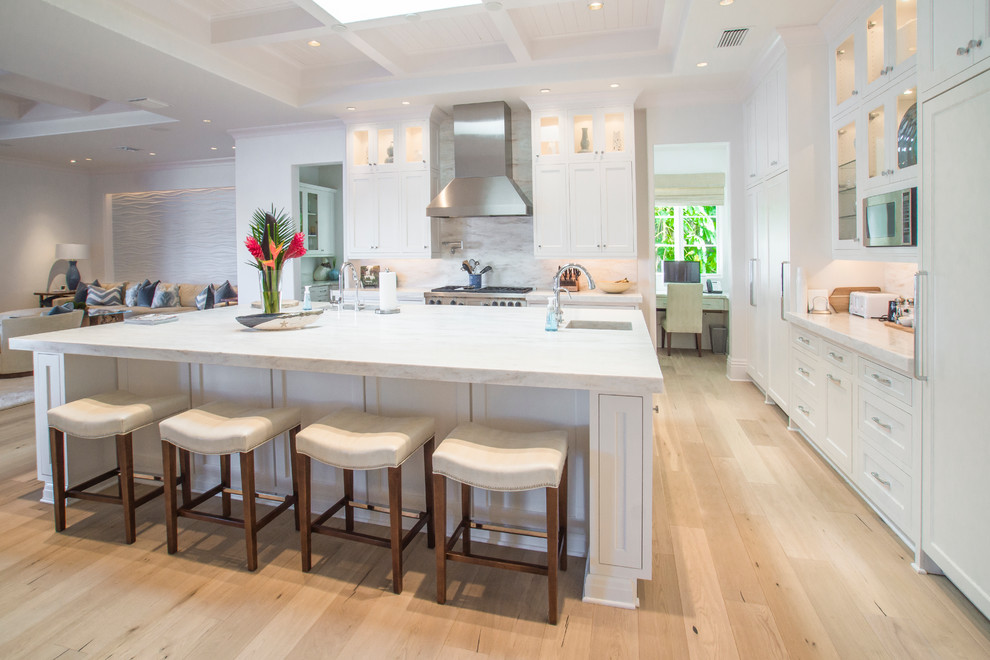 Design ideas for a transitional l-shaped open plan kitchen in Miami with glass-front cabinets, white cabinets, white splashback and panelled appliances.
