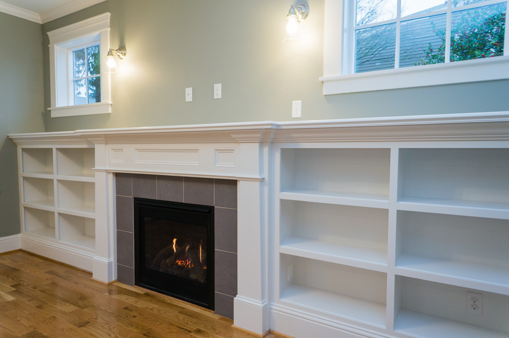 This is an example of a mid-sized arts and crafts open concept family room in Portland with light hardwood floors, a standard fireplace, a tile fireplace surround and a wall-mounted tv.