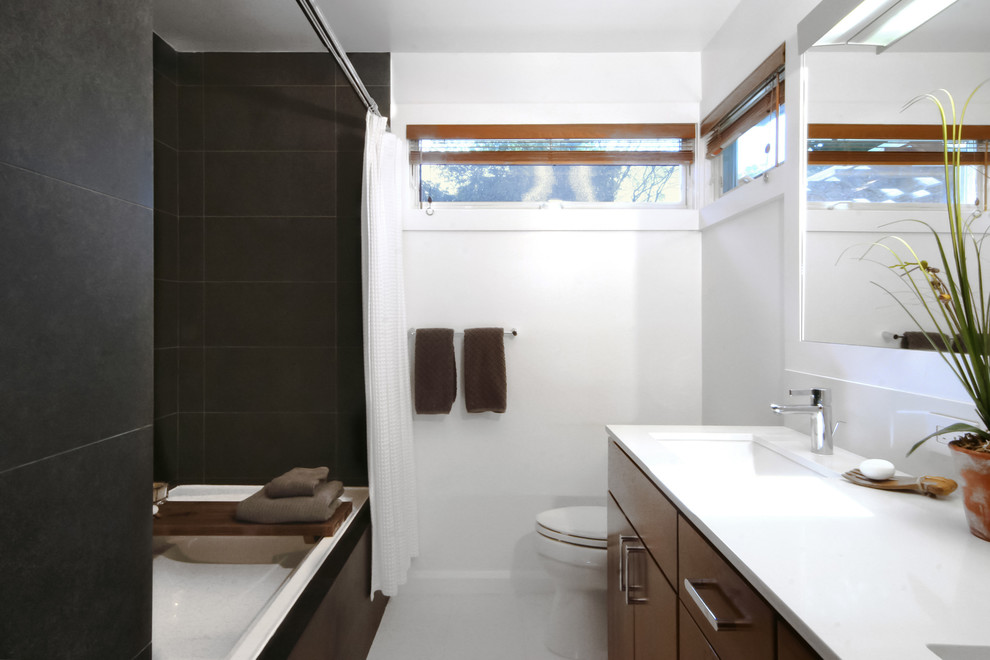 Small modern master bathroom in New York with flat-panel cabinets, dark wood cabinets, a drop-in tub, a shower/bathtub combo, a two-piece toilet, black tile, porcelain tile, white walls, porcelain floors, an undermount sink, engineered quartz benchtops, grey floor and a shower curtain.