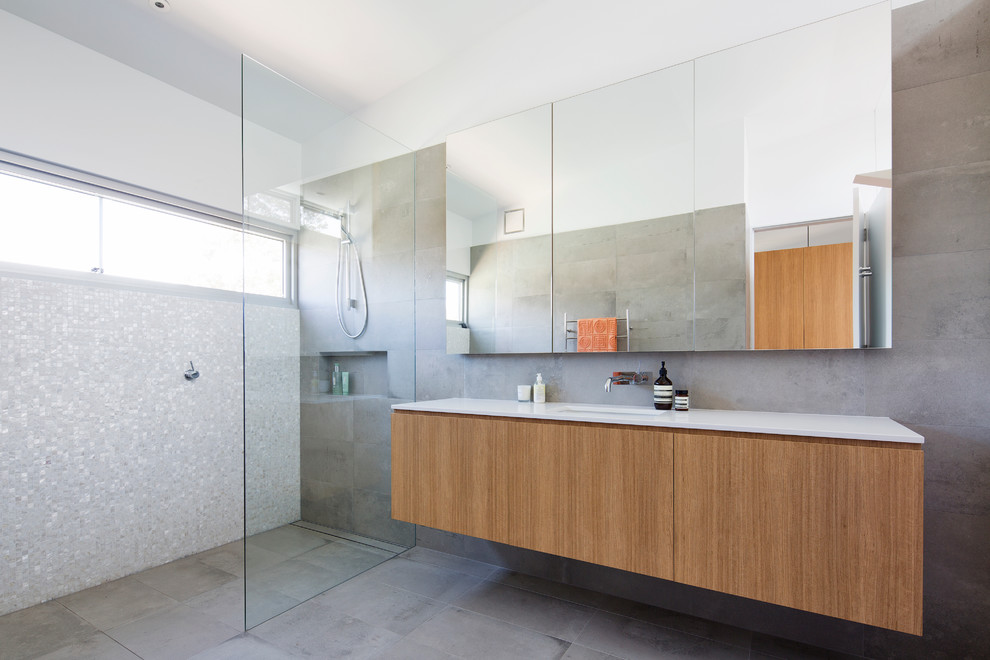 Large contemporary master bathroom in Sydney with light wood cabinets, a curbless shower, gray tile, porcelain tile, grey walls, ceramic floors, an undermount sink and solid surface benchtops.