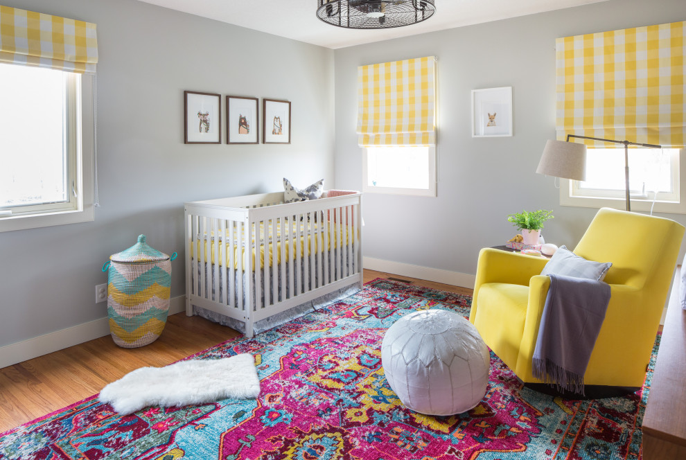 Idées déco pour une chambre de bébé fille campagne de taille moyenne avec un mur gris, un sol en bois brun et un sol marron.