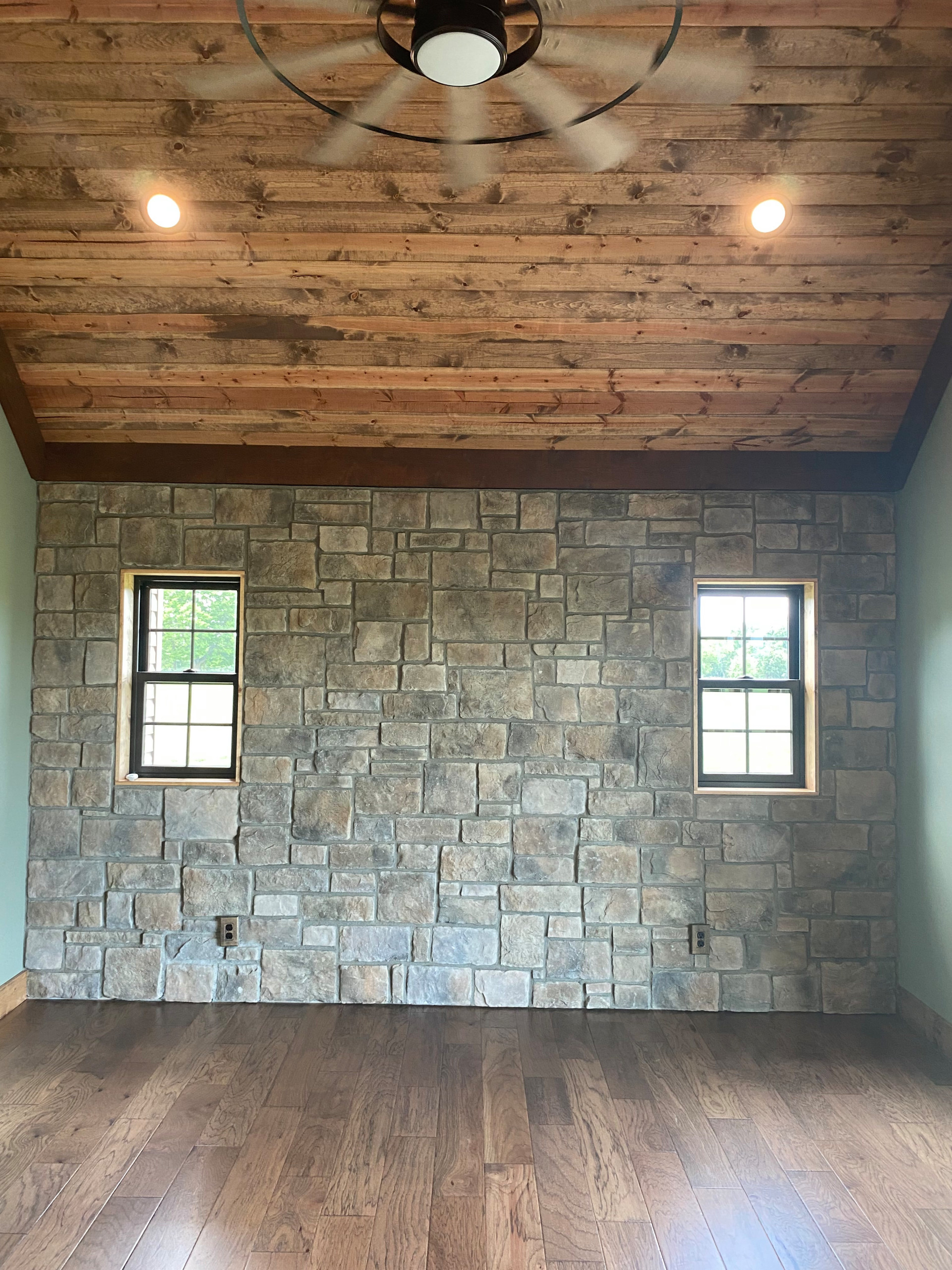 Master bedroom with stained carside ceiling and rock accent wall