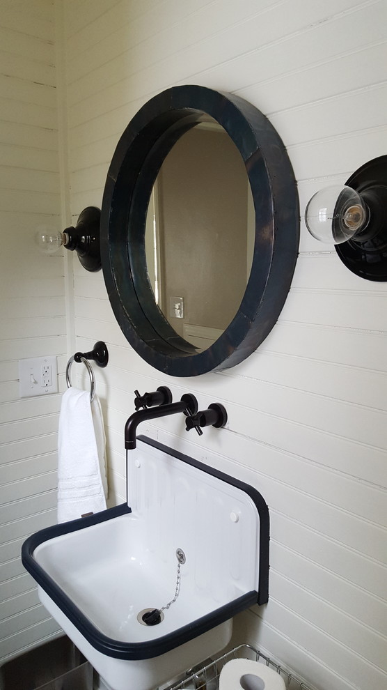 This is an example of a small industrial 3/4 bathroom in Milwaukee with a two-piece toilet, white tile, porcelain tile, white walls, porcelain floors and a wall-mount sink.