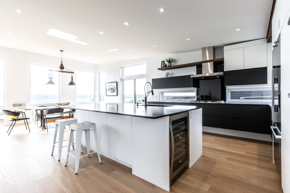 Design ideas for a large modern galley eat-in kitchen in New York with a drop-in sink, flat-panel cabinets, white cabinets, quartz benchtops, black splashback, ceramic splashback, stainless steel appliances, ceramic floors, with island, brown floor and black benchtop.