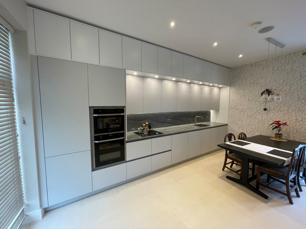 Exempel på ett mellanstort modernt grå linjärt grått kök och matrum, med en undermonterad diskho, släta luckor, grå skåp, granitbänkskiva, grått stänkskydd, rostfria vitvaror, klinkergolv i porslin och beiget golv