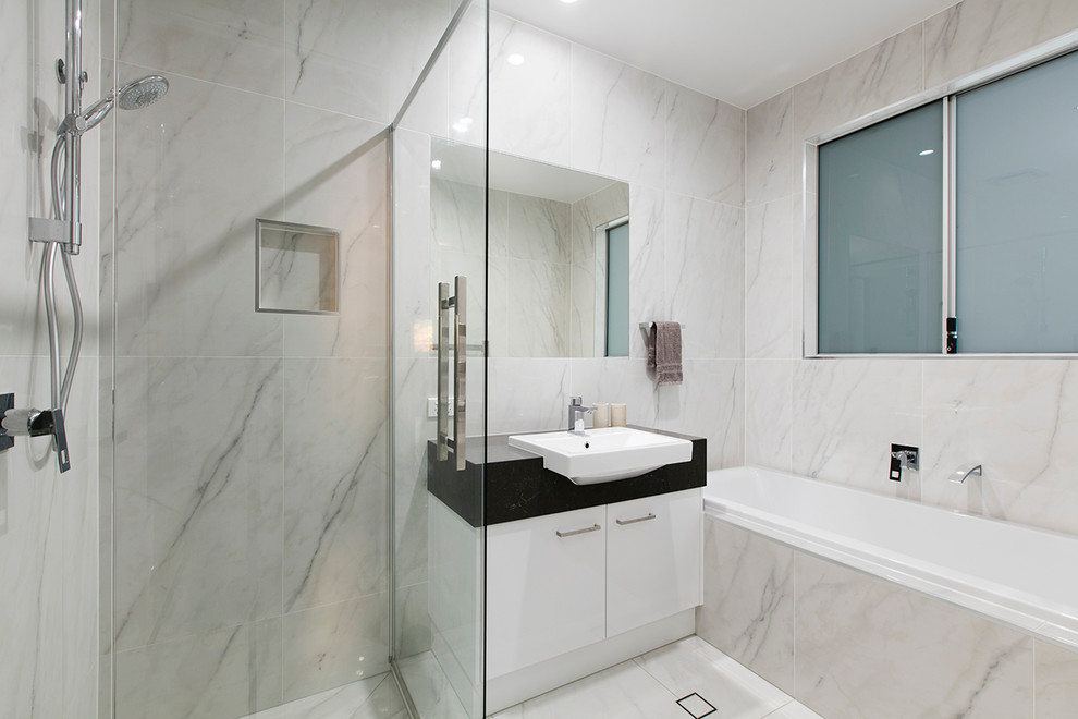 This is an example of a contemporary master bathroom in Brisbane with flat-panel cabinets, white cabinets, a drop-in tub, a corner shower, gray tile, white tile, white walls and a drop-in sink.