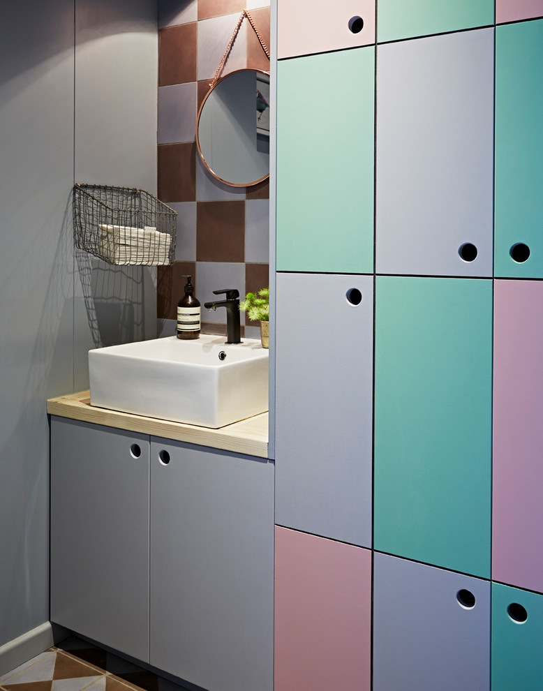 This is an example of an eclectic powder room in London with flat-panel cabinets and purple walls.