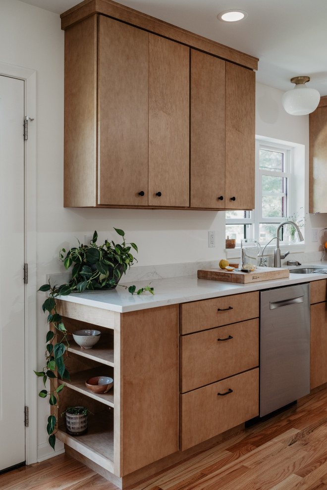 Example of a mid-sized 1960s l-shaped medium tone wood floor kitchen pantry design in Detroit with an undermount sink, flat-panel cabinets, light wood cabinets, quartz countertops, white backsplash, quartz backsplash, stainless steel appliances, a peninsula and white countertops