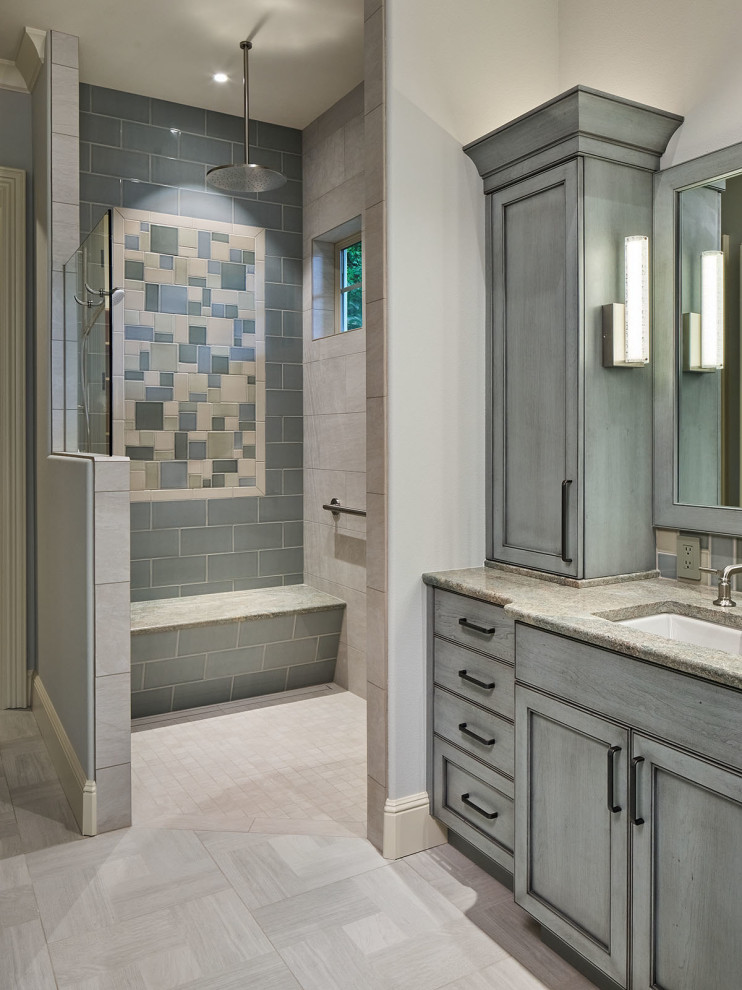 This is an example of a large country master bathroom in Portland with recessed-panel cabinets, blue cabinets, a freestanding tub, a curbless shower, multi-coloured tile, porcelain tile, grey walls, porcelain floors, an undermount sink, granite benchtops, grey floor, an open shower, multi-coloured benchtops, an enclosed toilet, a double vanity and a freestanding vanity.
